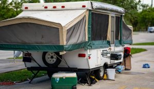 Pop-up rv camper at a camp ground with a cooler and barbecue on site