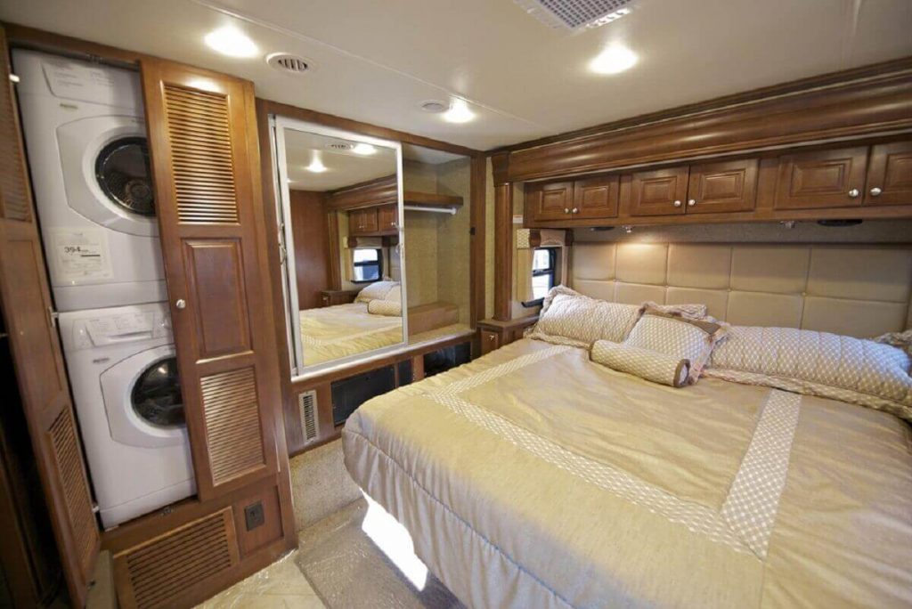 Luxurious RV bedroom interior with a washer and dryer combo in closet in bedroom
