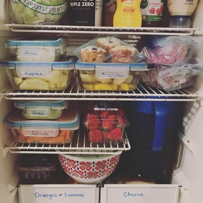 An efficiently organized RV fridge with clearly marked food containers neatly packed.