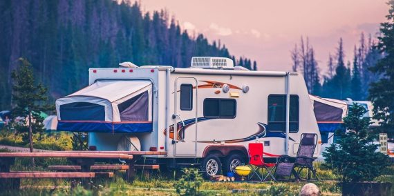 A pop camper travel trailer parked at an RV campsite.